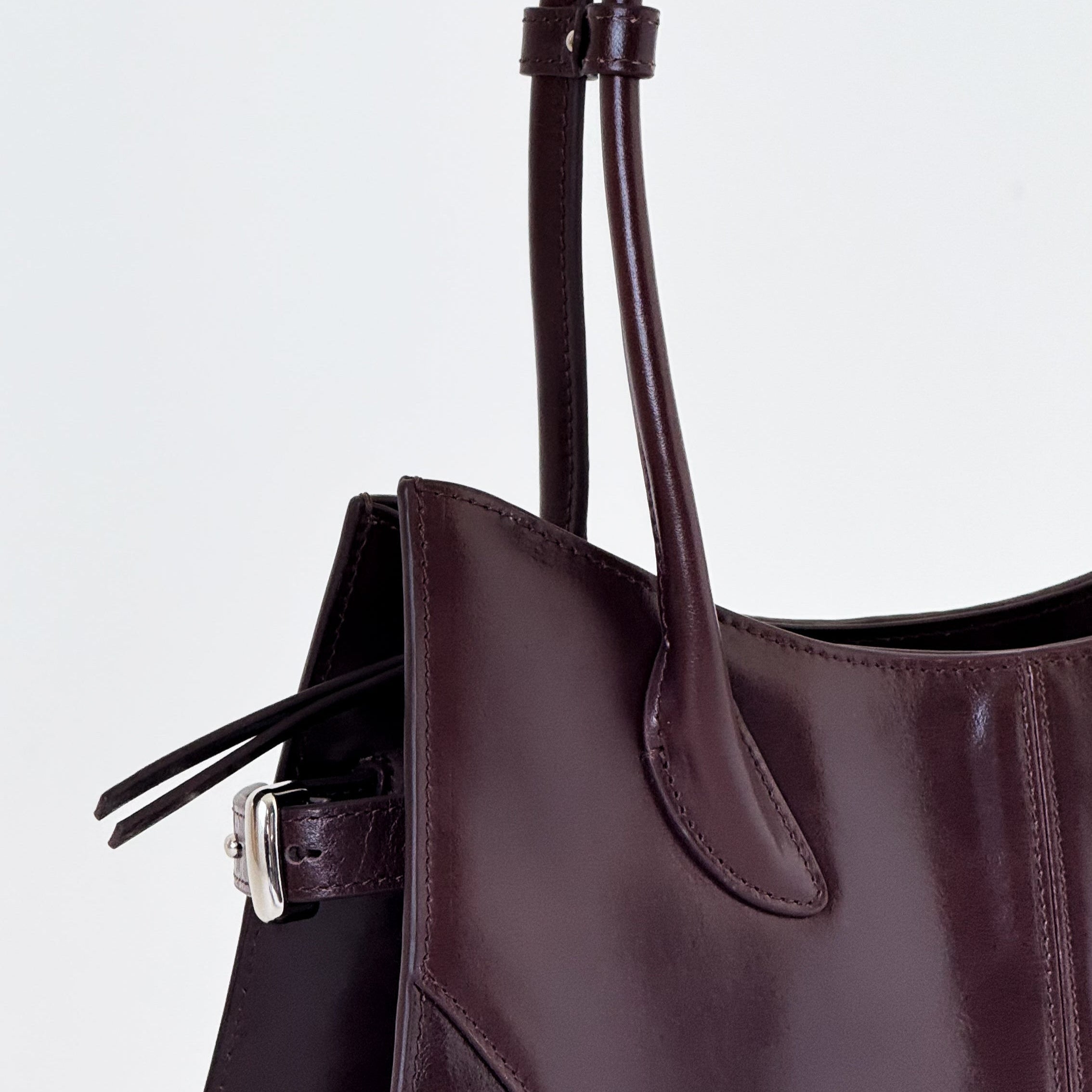 Close-up of a dark brown handbag with a light gray background