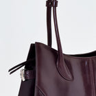 Close-up of a dark brown handbag with a light gray background